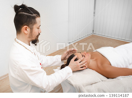 Chiropractor doing energetic head massage. Woman getting reiki therapy. Alternative medicine Chiropractor doing energetic head massage. Woman getting reiki therapy. Alternative medicine 139114187