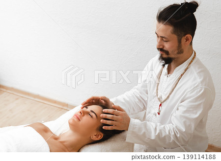 Doctor of traditional oriental medicine doing energetic head massage. Energetic massage resumes the circulation of energy in body Doctor of traditional oriental medicine doing energetic head massage. Energetic massage resumes the circulation of energy in body 139114188
