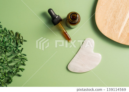 Rose quartz gua sha tool and oil bottle on wooden tray, face massage tool, beauty abstract photo. Copy space Rose quartz gua sha tool and oil bottle on wooden tray, face massage tool, beauty abstract photo. Copy space 139114569