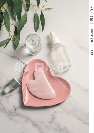 Rose quartz gua sha and oil bottles, abstract beauty photo Rose quartz gua sha and oil bottles, abstract beauty photo 139114572