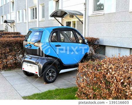Small electric city car parked near residential building. Small electric city car parked near residential building. 139116603