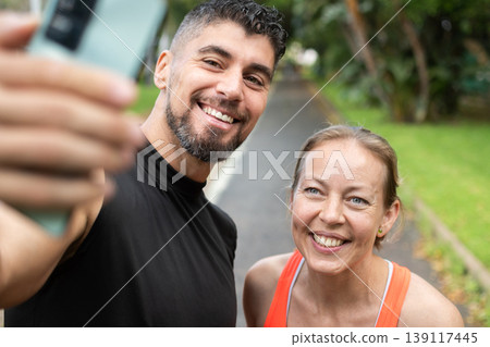 Smiling personal trainer taking a selfie with a mature female Smiling personal trainer taking a selfie with a mature female 139117445