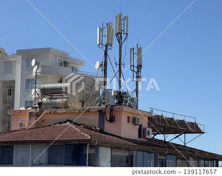 Cellular antennas on rooftop against clear blue sky, communication technology infrastructure. 139117657