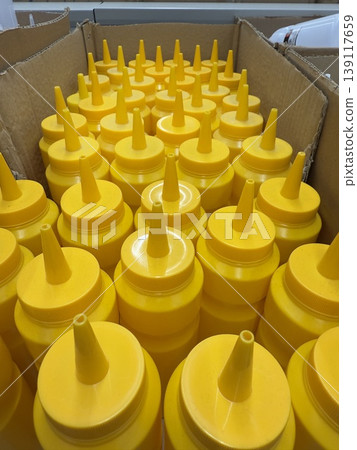 Yellow squeeze bottles arranged in cardboard box from top angle for condiment storage Yellow squeeze bottles arranged in cardboard box from top angle for condiment storage 139117659