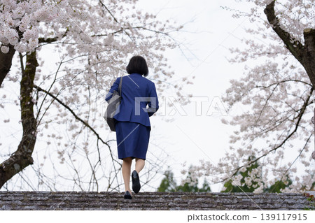 The back view of a woman in a suit outdoors in springtime. The back view of a woman in a suit outdoors in springtime. 139117915
