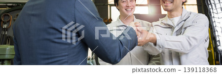 A scene of trust between a salesman and a worker shaking hands in a manufacturing plant; a business contract or agreement scene; faceless. 139118368