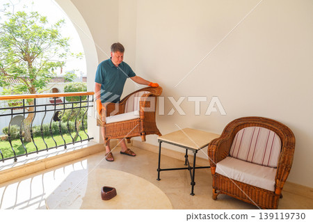 A man rearranges furniture, moves a chair to a new location A man rearranges furniture, moves a chair to a new location 139119730