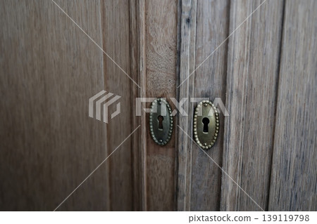 A keyhole in a wooden door. An old, decorative brass keyhole. Antique-style interior. A keyhole in a wooden door. An old, decorative brass keyhole. Antique-style interior. 139119798