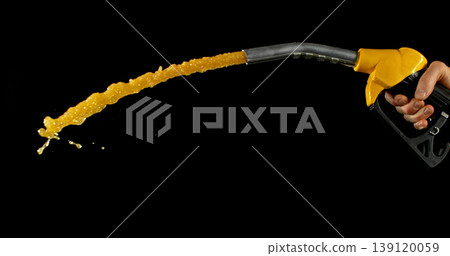 Gasoline jet spraying from fuel nozzle held by hand on dark background. Dynamic liquid motion, refueling concept, energy supply, fuel usage, dramatic lighting, macro detail. Gasoline jet spraying from fuel nozzle held by hand on dark background. Dynamic liquid motion, refueling concept, energy supply, fuel usage, dramatic lighting, macro detail. 139120059
