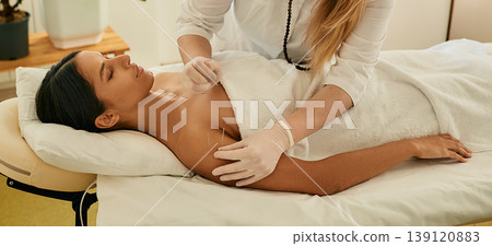 Adult woman relaxing and enjoying during acupuncture procedure. Shoulder acupressure, puncture of a meridian point on body patient Adult woman relaxing and enjoying during acupuncture procedure. Shoulder acupressure, puncture of a meridian point on body patient 139120883