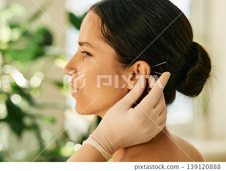 Woman having ear acupressure or ear acupuncture for her diseases treatment, side view. Acupuncture, reflexology, traditional Chinese medicine Woman having ear acupressure or ear acupuncture for her diseases treatment, side view. Acupuncture, reflexology, traditional Chinese medicine 139120888