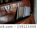 Black DDR5 RAM memory modules placed inside a brown leather bag pocket. RAM shortages on the market, rising prices, and increased demand driven by the growing need for AI training. 139121448