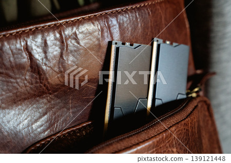 Black DDR5 RAM memory modules placed inside a brown leather bag pocket. RAM shortages on the market, rising prices, and increased demand driven by the growing need for AI training. Black DDR5 RAM memory modules placed inside a brown leather bag pocket. RAM shortages on the market, rising prices, and increased demand driven by the growing need for AI training. 139121448