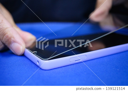 The hands applying the glass screen protector to a smartphone The hands applying the glass screen protector to a smartphone 139121514