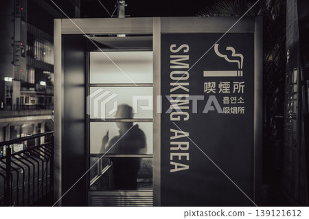 深夜,一名男子在吸菸區手持加熱煙草製品。 深夜,一名男子在吸菸區手持加熱煙草製品。 139121612