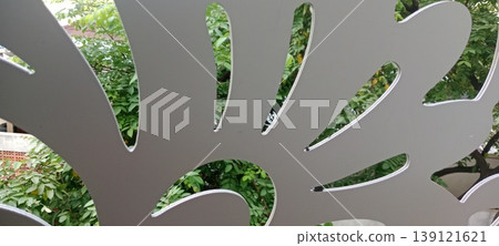 View of green foliage through decorative laser cut panel with abstract pattern View of green foliage through decorative laser cut panel with abstract pattern 139121621