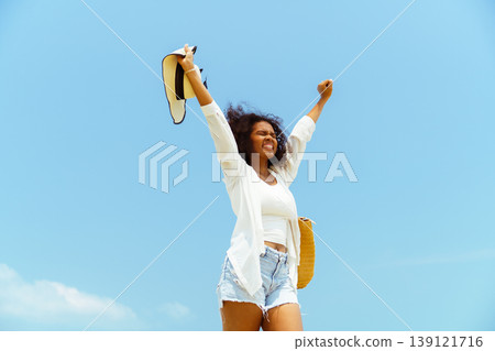 Happy black woman with arms up on summer vacation beach trip 139121716