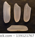 Four grains of uncooked rice, isolated on a dark background. 139121767