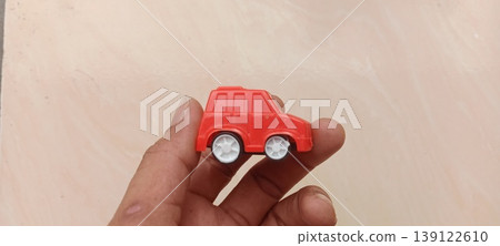 Miniature red plastic toy car in palm Miniature red plastic toy car in palm 139122610