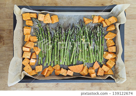Fresh green asparagus and sweet potato cubes on metal roasting pan, natural light, colorful healthy vegetable dish, view above Fresh green asparagus and sweet potato cubes on metal roasting pan, natural light, colorful healthy vegetable dish, view above 139122674