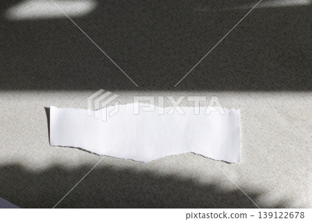 A blank, torn piece of white paper resting on a dark, textured surface A blank, torn piece of white paper resting on a dark, textured surface 139122678