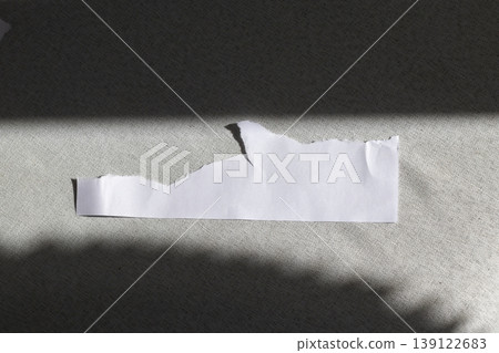 A blank, torn piece of white paper resting on a dark, textured surface A blank, torn piece of white paper resting on a dark, textured surface 139122683