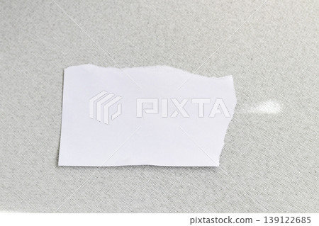 A blank, torn piece of white paper resting on a dark, textured surface A blank, torn piece of white paper resting on a dark, textured surface 139122685