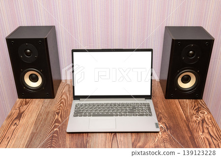 open gray laptop with a white screen stands on a wooden table between two black speakers open gray laptop with a white screen stands on a wooden table between two black speakers 139123228
