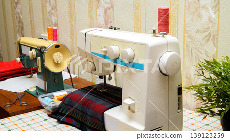 sewing process on a white sewing machine with accessories on the table sewing process on a white sewing machine with accessories on the table 139123259