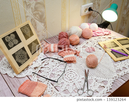 side view of a crochet workspace with yarn balls and patterns 139123264