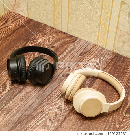 wireless headphones in black and beige colors on a wooden table side view wireless headphones in black and beige colors on a wooden table side view 139123381