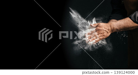 Chef clapping flour creating powder explosion on dark background with copy space 139124000