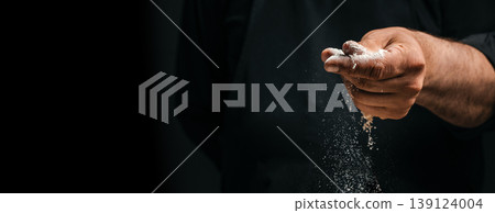 Hand sprinkling flour in air over dark background baking concept with copy space 139124004