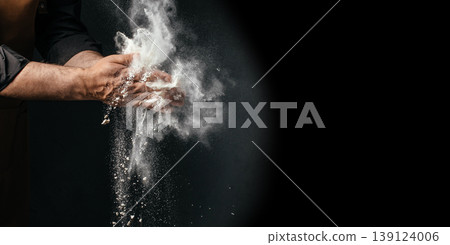 Chef clapping flour in air on dark background with large copy space baking concept Chef clapping flour in air on dark background with large copy space baking concept 139124006