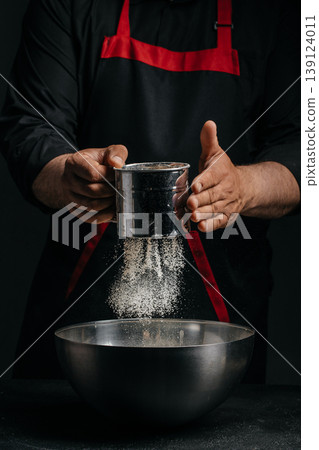 Chef sifting flour into bowl baking preparation concept with copy space 139124011