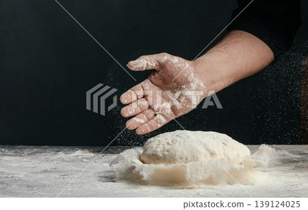 Baker hand sprinkling flour over raw dough on dark background artisan baking process with copy space Baker hand sprinkling flour over raw dough on dark background artisan baking process with copy space 139124025