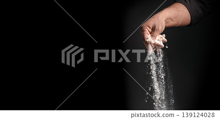 Hand pouring flour in vertical stream on dark background with large copy space 139124028