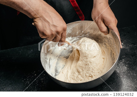 Mixing sticky dough in metal bowl with spoon baking process close up Mixing sticky dough in metal bowl with spoon baking process close up 139124032