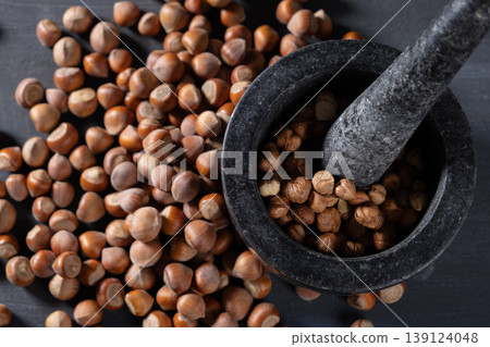 Raw hazelnuts in a stone mortar against a dark background Raw hazelnuts in a stone mortar against a dark background 139124048
