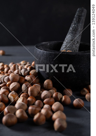 Raw hazelnuts in a stone mortar against a dark background Raw hazelnuts in a stone mortar against a dark background 139124049