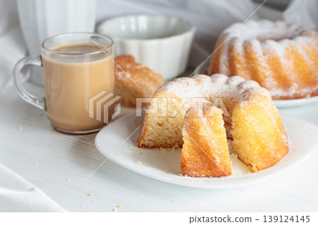 Traditional vanilla pound cake with orange extract and coffee latte on a white table. Traditional vanilla pound cake with orange extract and coffee latte on a white table. 139124145