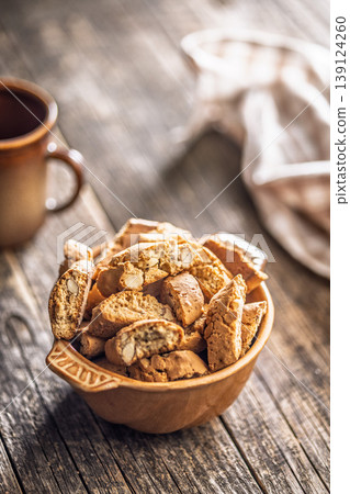 Rustic Almond Biscotti cantuccini in Ceramic Bowl With Coffee Cup on Weathered Wooden Table 139124260