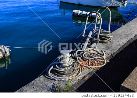 Mooring line on rusty pier referred to a post on a ship or quay. Mooring line on rusty pier referred to a post on a ship or quay. 139124458