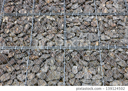 Gabion Wire Mesh Filled with Rocks, steel net as security against falling rocks.Gabion Wire Mesh Filled with Rocks, steel net as security against falling rocks. Gabion Wire Mesh Filled with Rocks, steel net as security against falling rocks.Gabion Wire Mesh Filled with Rocks, steel net as security against falling rocks. 139124502