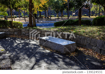 A classic rock bench in shady park in autumn. A classic rock bench in shady park in autumn. 139124531