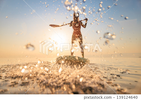 Silhouette of girl walking on sup board by the sea during summer vacation Silhouette of girl walking on sup board by the sea during summer vacation 139124640