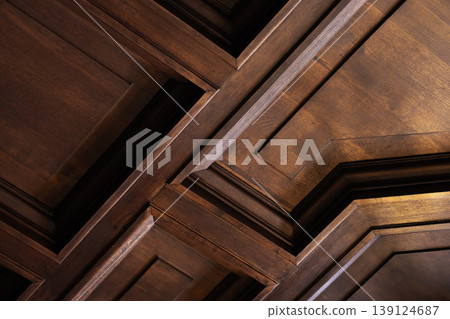 Close-up of a dark wood coffered ceiling showcasing geometric raised panels Close-up of a dark wood coffered ceiling showcasing geometric raised panels 139124687