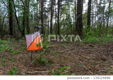 Orienteering control point with orange and white flag 139124896