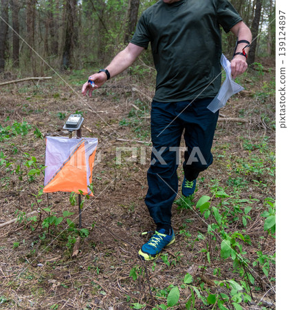 A male orienteer in a green shirt and blue shoes A male orienteer in a green shirt and blue shoes 139124897