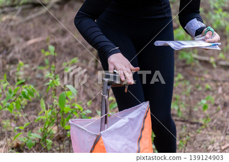 Athlete punches electronic timing device at orienteering control point 139124903